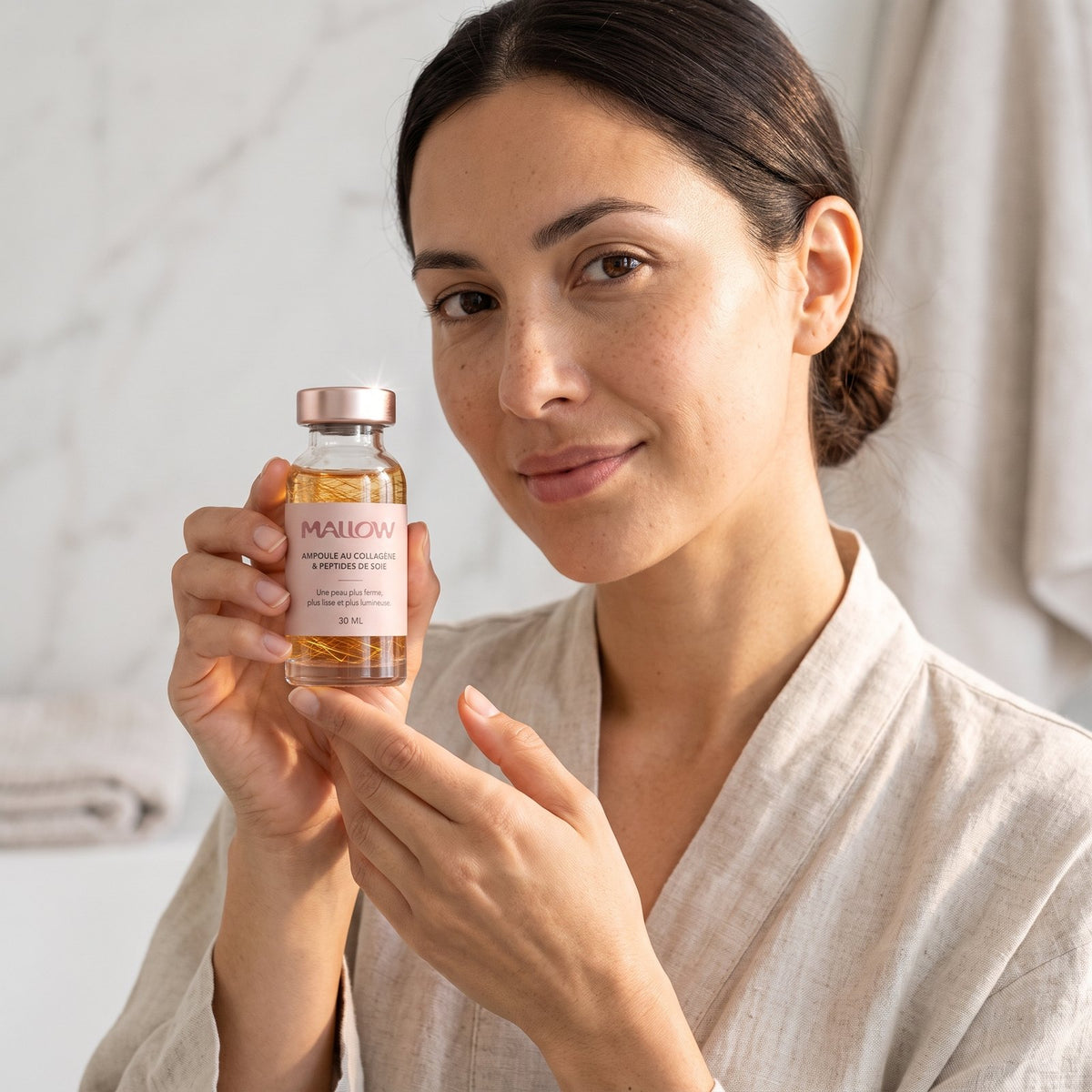 Femme en peignoir présentant le sérum Mallow