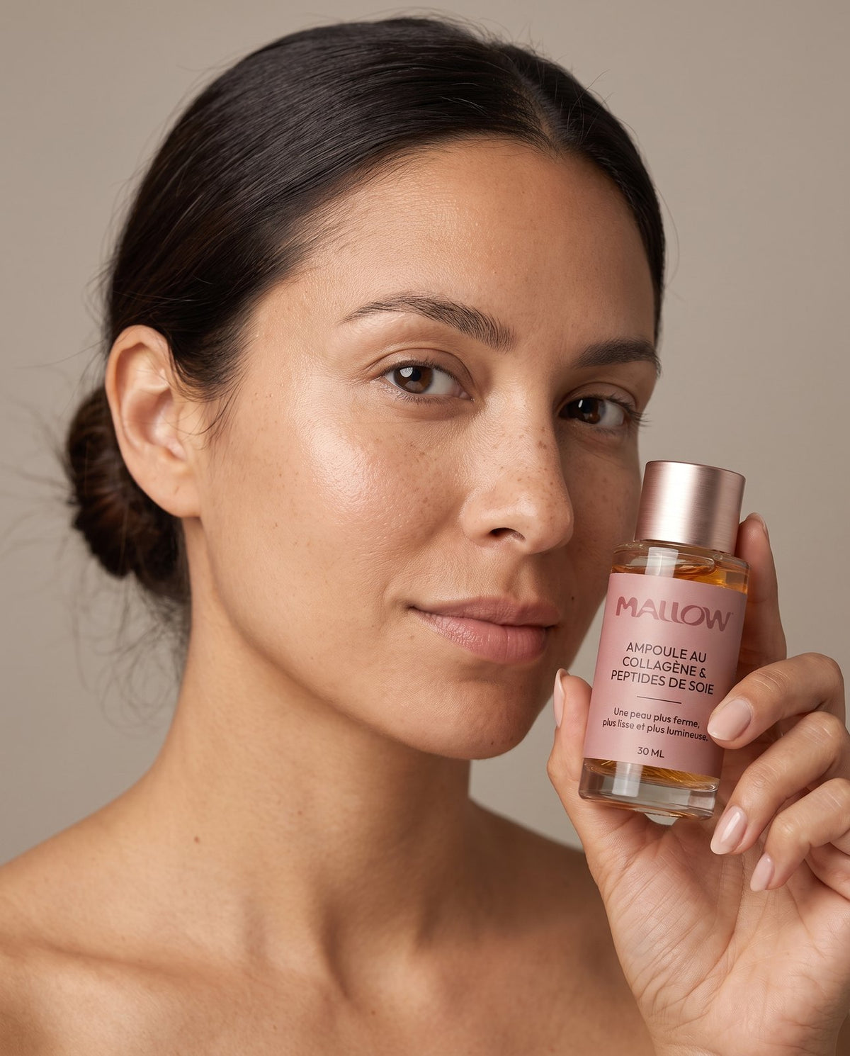 Femme tenant le sérum Mallow contre sa joue